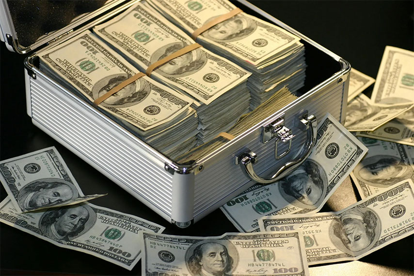 A metal case full of money with more $100 bills lying around