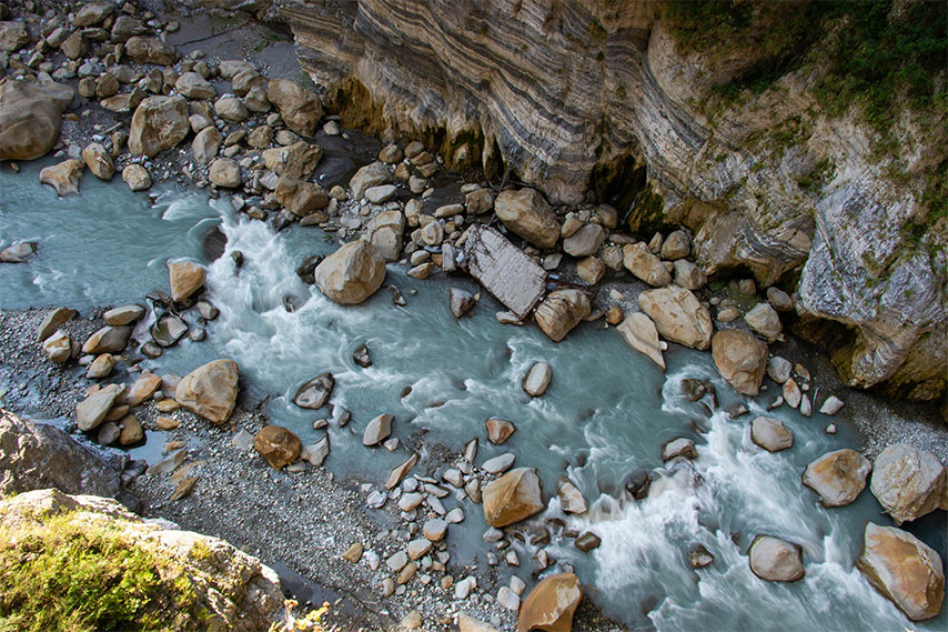 A top view of a creek with large boulders near cliffs