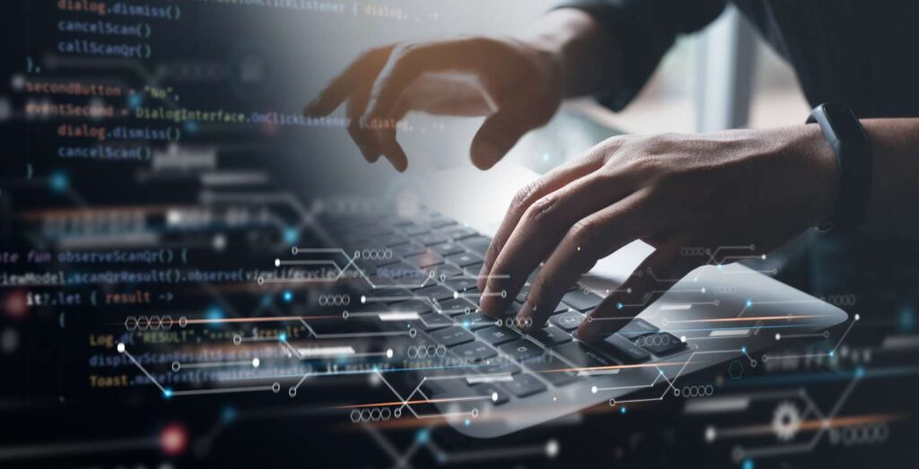 Close-up of the hands of a software engineer working on a laptop with a circuit board and lines of code shown on a virtual screen