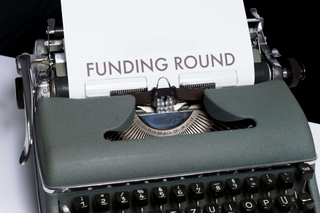 A typewriter with a piece of paper and the words Funding Round