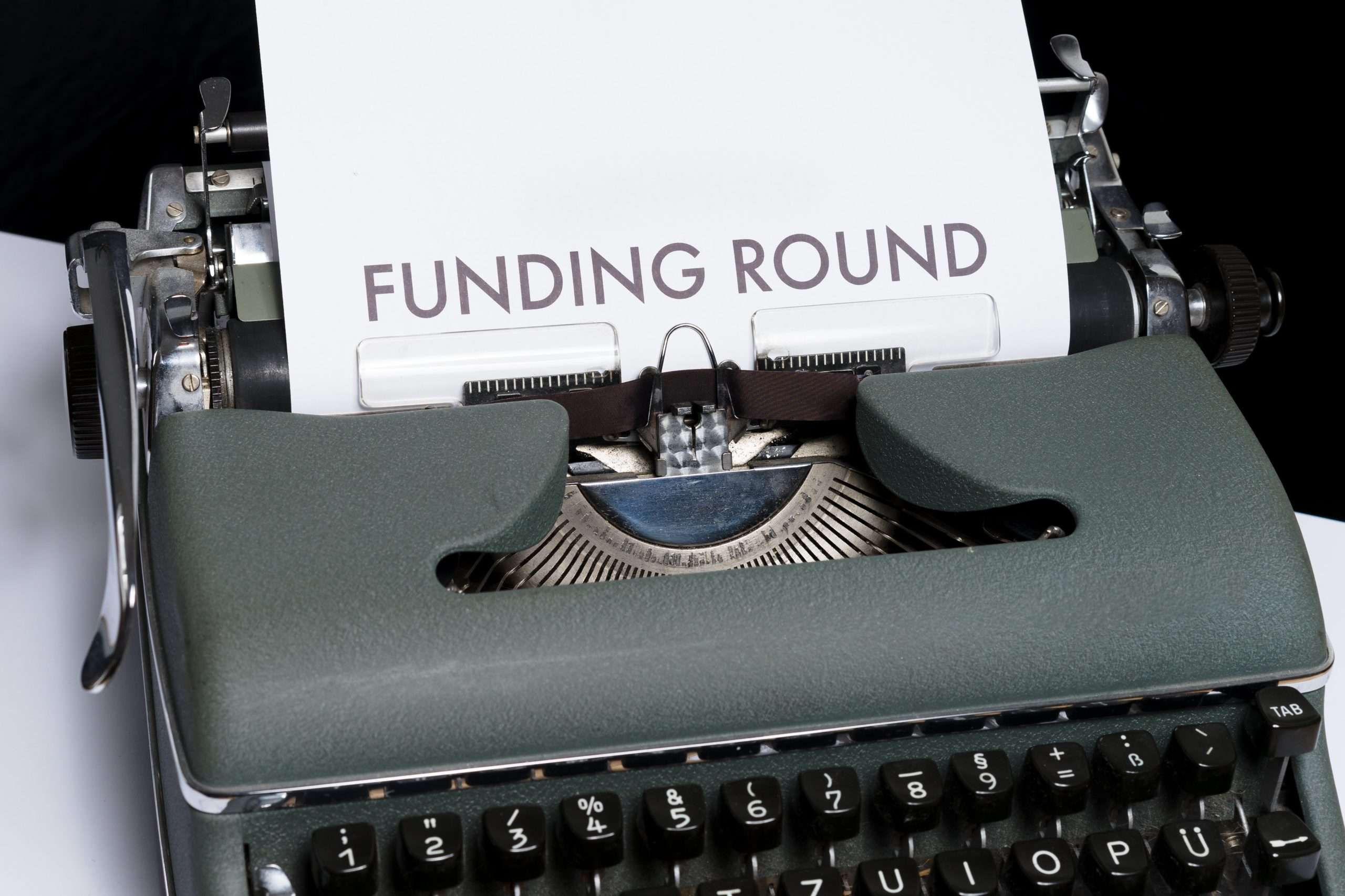 A typewriter with a piece of paper and the words Funding Round